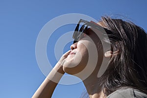 Woman is looking on solar eclipse through three sunglasses.