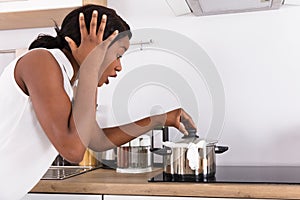 Woman Looking At Spilling Out Boiled Milk From Utensil