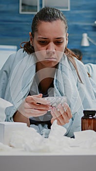Woman looking at tablets of capsules and jar of pills on table