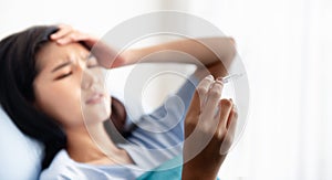 Woman looking at the thermometer and headache photo