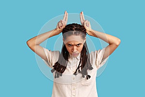 Woman looking threatening showing bull horn sign, holding fingers on her head, conflicting person.
