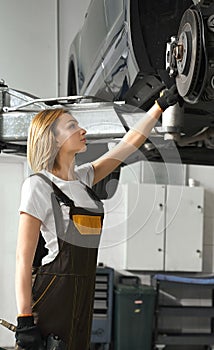 Woman looking at tire of car in auto service