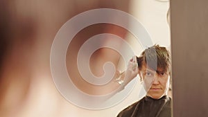 Woman looking to mirror, barber cutting hair in barbershop