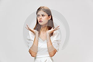 Woman looking to the side displeased facial expression hands in front of her gray background