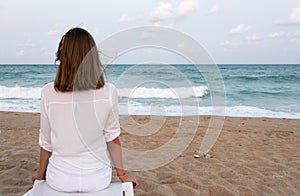 Woman looking to a tidal waves roll onto a sandy beach