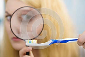 Woman looking at toothbrush through loupe
