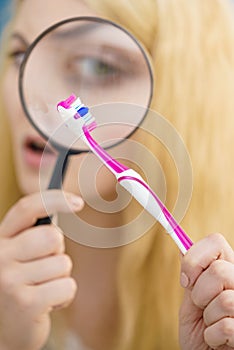 Woman looking at toothbrush through loupe