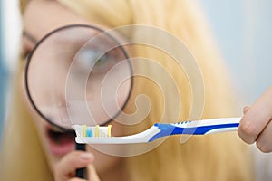 Woman looking at toothbrush through loupe