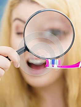 Woman looking at toothbrush through loupe