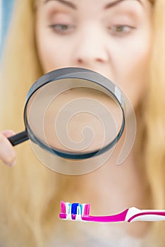 Woman looking at toothbrush through loupe