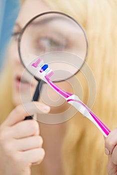 Woman looking at toothbrush through loupe