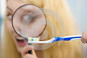 Woman looking at toothbrush through loupe