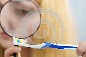 Woman looking at toothbrush through loupe