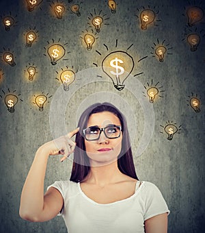 Woman looking up at dollar idea light bulbs above head deciding how to earn morney