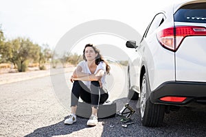 Woman looking upset with flat tyre on her car