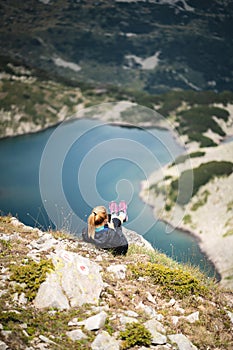 Woman Looking Using her Phone sitting on the edge of a Beautiful Mountain
