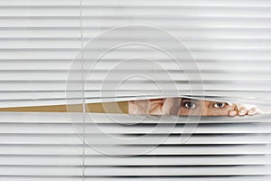 Woman Looking Through Venetian Blinds