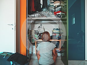 Woman looking at wardrobe, home interior, desperate housewife, cleaning home, rear view sitting, toned vintage style.