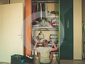 Woman looking at wardrobe, home interior, desperate housewife, cleaning home, rear view sitting, toned vintage style.