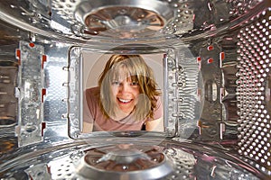 Woman looking into washing machine at laundromat without clothing. Woman checking laundry from top load washing machine