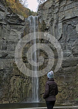 woman looking at waterfall in Taughannock Falls State Park (cayuga lake ithaca ny) fall foliage in brown jacket hat