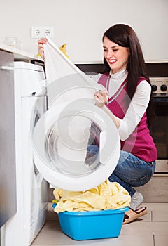 Woman looking white clothes near washing machine