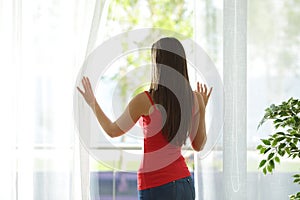 Woman looking through a window at home photo