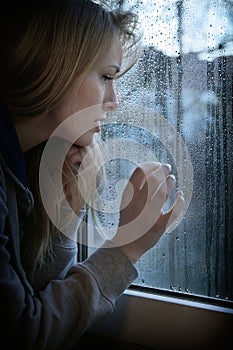 Woman looking through window with raindrops