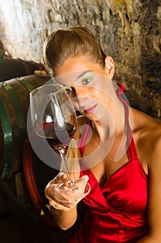 Woman looking at wine glass in the cellar