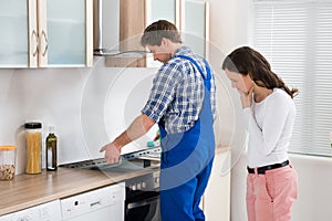 Woman Looking At Worker Repairing Induction Hob