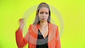 Woman looking at wrist watch in space studio on yellow background