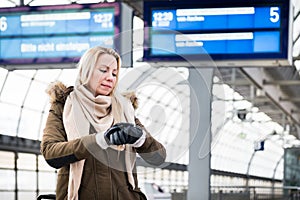 Woman looking at wristwatch in train station as her train has a delay