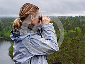 Woman looks through binoculars.