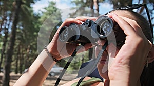 Woman Looks Through Binoculars on a Chaise Longue in a Forest near Camping