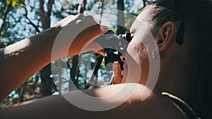 Woman Looks Through Binoculars on a Chaise Longue in a Forest near Camping