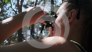 Woman Looks Through Binoculars on a Chaise Longue in a Forest near Camping