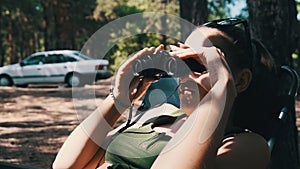 Woman Looks Through Binoculars on a Chaise Longue in a Forest near Camping