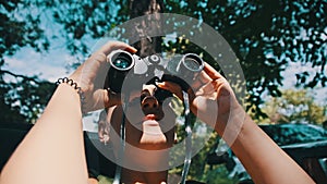 Woman Looks Through Binoculars on a Chaise Longue in a Forest near Camping