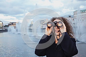 Woman looks through binoculars at sunset