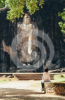 Woman looks on Buduruwagala - oldest Buddha statue in Sri Lanka