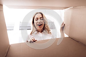 A woman looks into the empty box from the inside. Close-up photo of a woman peering into box.