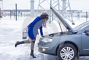 Woman looks at the engine of her car and holding a manual car