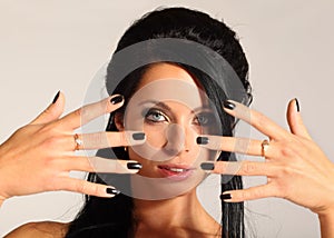 Woman looks through fingers, black manicure