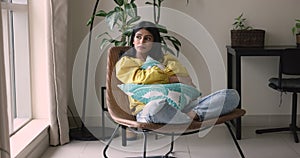 Woman looks frustrated or offended cuddling cushion sit in armchair