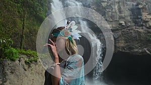 Woman looks like indian shaman in forest with waterfall
