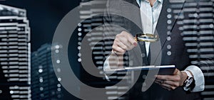 A woman looks through a magnifying glass at a document