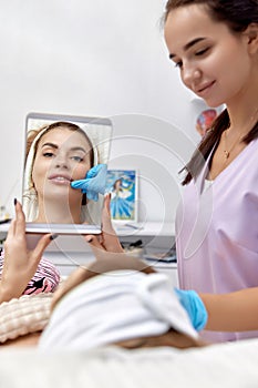 woman looks at mirror after procedure lip augmentation