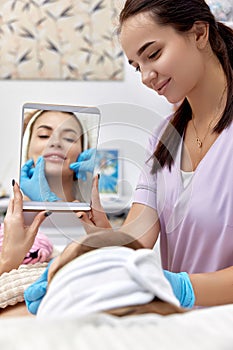 woman looks at mirror after procedure lip augmentation