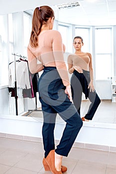 Woman looks in the mirror trying on pants
