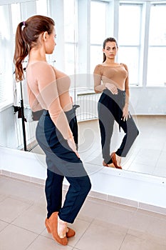 Woman looks in the mirror trying on pants